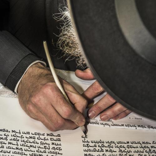 Photo of a Jewish man writing Hebrew scripture
